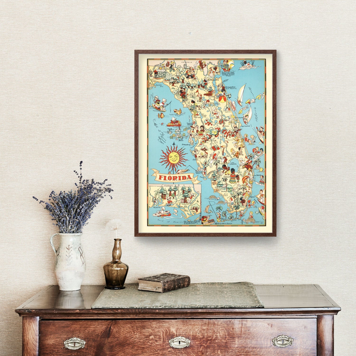 Framed vintage-style map of Florida with colorful illustrations, displayed on a wall above a wooden dresser with decorative items.