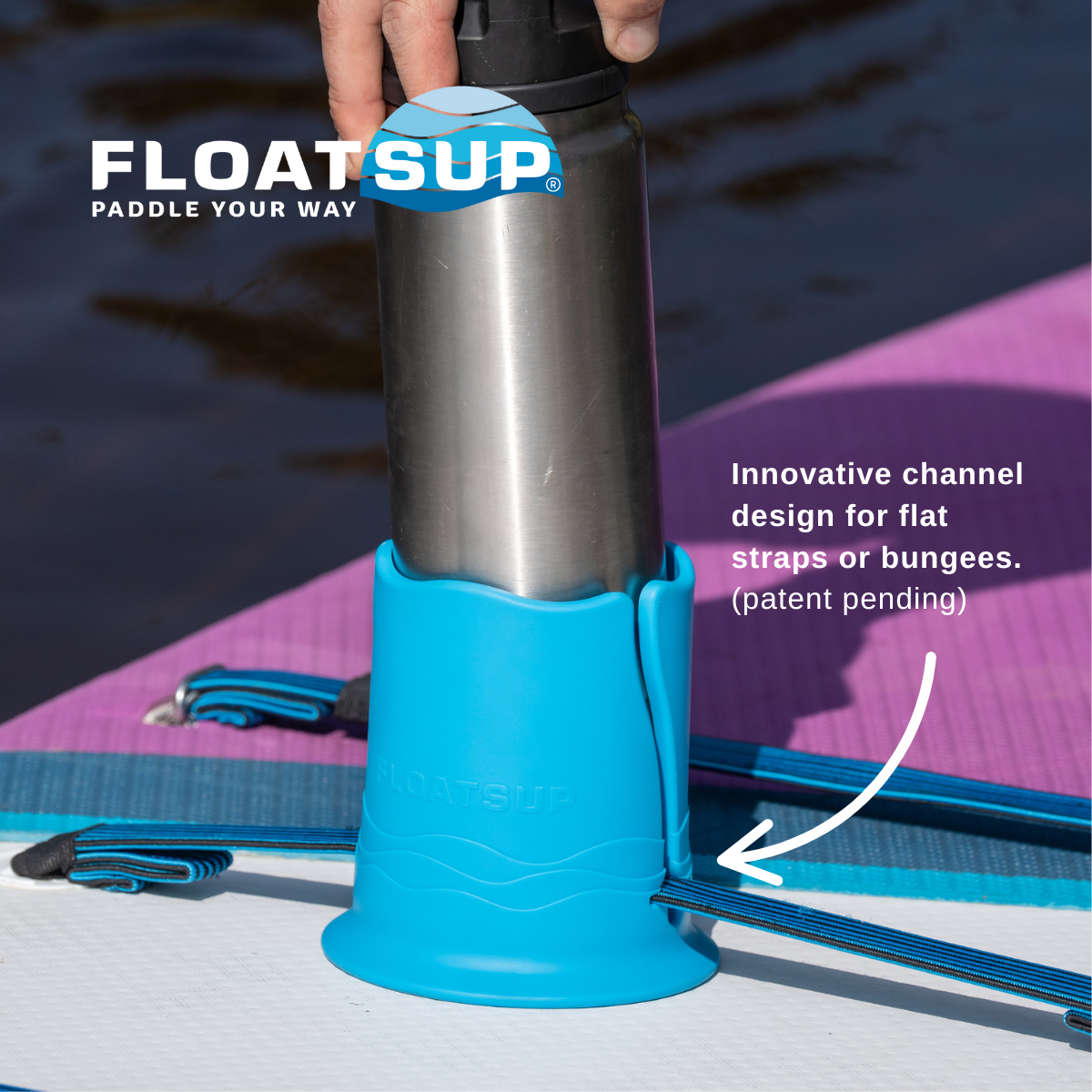 A hand is placing a metal water bottle into a blue cup holder attached to a purple paddleboard in the water. There is text saying 'Innovative channel design for flat straps or bungees. (patent pending)' and the Floatsup logo is shown in the top left corner.