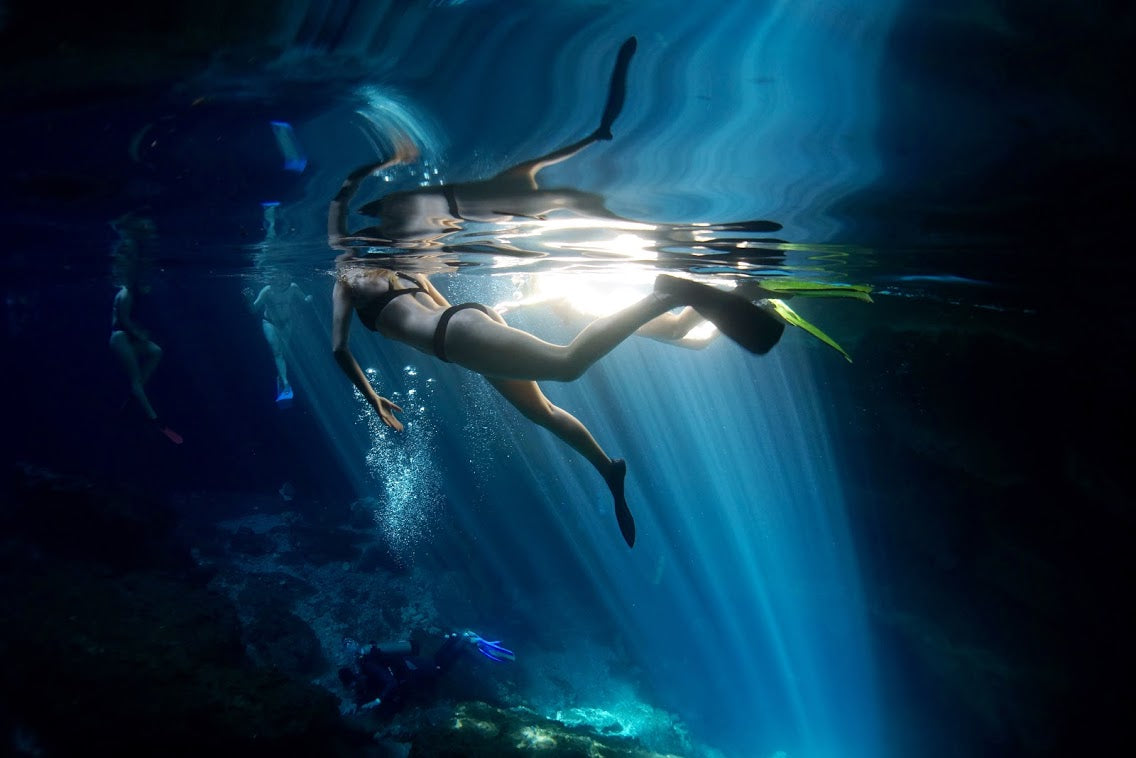 Person snorkeling underwater with sunlight filtering through the water.